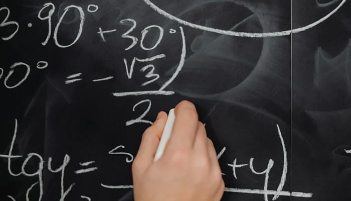 This representational image shows a person solving a maths problem. — Pexels