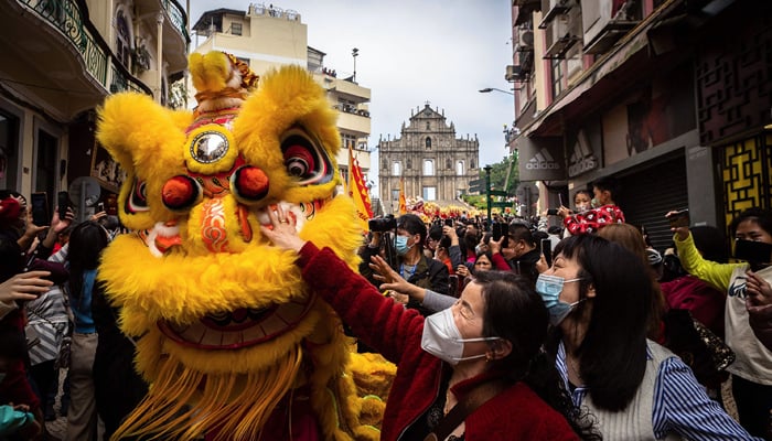 Women reach to touch a traditional Lion dance performer for good luck in front of the Ruins of St. Pauls during Lunar New Year celebrations. — AFP/File
