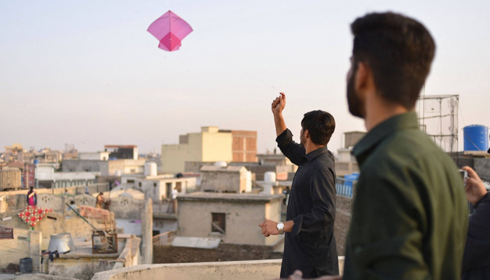 Youths fly kites from a rooftop during the Basant Kite Festival in Rawalpindi. — AFP/File