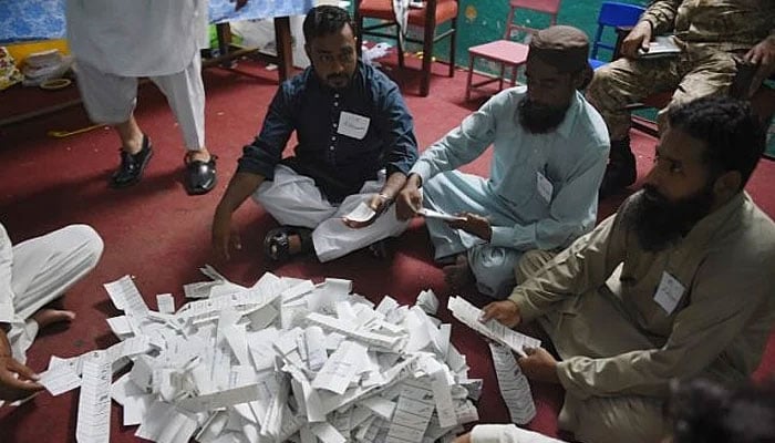 Pakistani election officials count ballots after polls closed at a polling station in Rawalpindi on July 25, 2018. — AFP