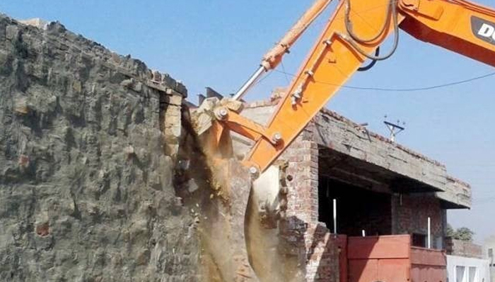 This image shows a bulldozer destroying an encroached structure. — INP/File