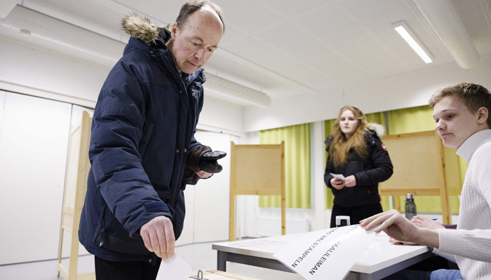 The Finns Party presidential candidate Jussi Halla-aho casts his vote as his daughter looks on at a polling station set up in a school in Helsinki, Finland, during the first round of the presidential election, on January 28, 2024. — AFP