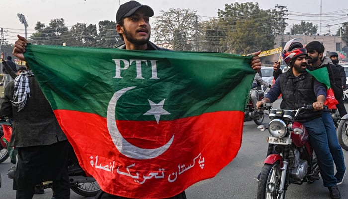 A supporter and activist of the Pakistan Tehreek-e-Insaf (PTI) party holds the party´s flag as he takes part in an election campaign rally in Lahore on January 28, 2024, ahead of the upcoming general elections. — AFP