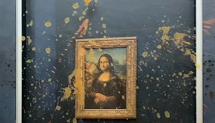 This image grab taken from AFPTV footage shows two environmental activists from the collective dubbed Riposte Alimentaire (Food Retaliation) hurling soup at Leonardo Da Vincis Mona Lisa (La Joconde) painting, at the Louvre museum in Paris, on January 28, 2024. — AFP
