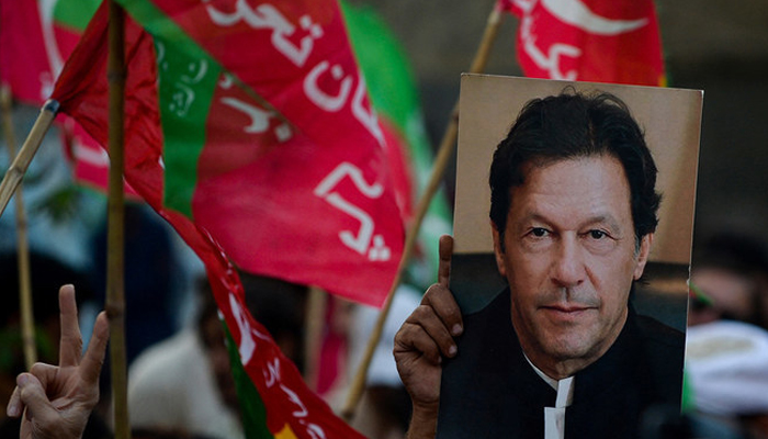 PTI supporters hold PTIs flags and former PM Imran Khans posters. — AFP/File