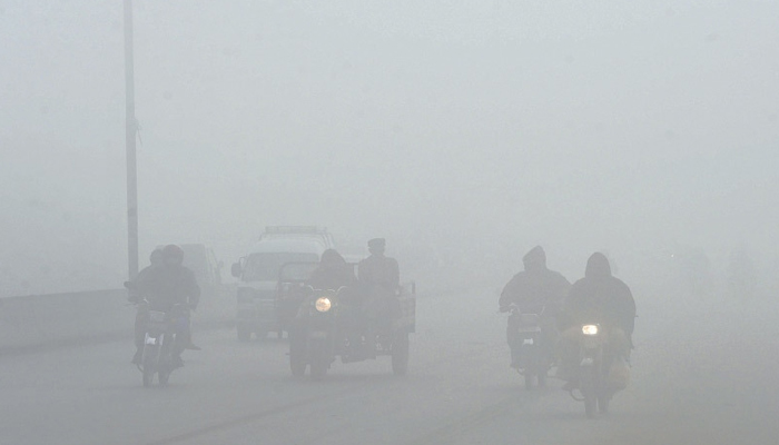 Motorists make their way along a street amid heavy fog. — AFP/File