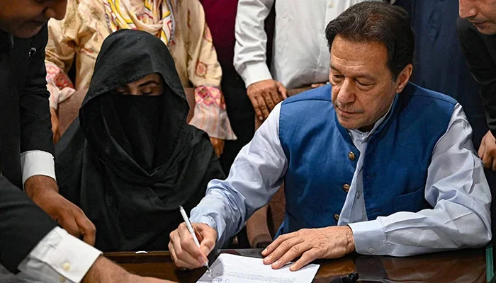 Former prime minister Imran Khan along with his wife Bushra Bibi signs surety bonds for bail in various cases, at the registrars office in the Lahore High Court on July 17, 2023. — AFP
