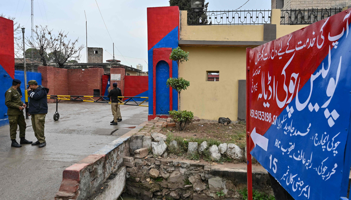 Police personnel stand guard near a signboard reading police check post Adiala at the entrance of Adiala jail in Rawalpindi on January 31, 2024. — AFP