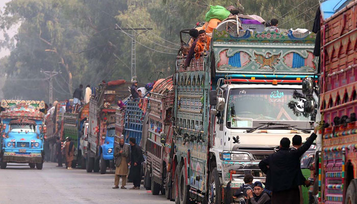 Trucks carrying Afghan immigrants queue up to leave for the border area from Nowshehra on October 30, 2023. — APP