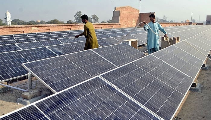 Workers washing 300 KWP solar PV system after its installation at Nishtar Medical University and Hospital in Multan, on December 4, 2022. — APP