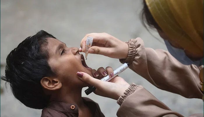 A health worker administers polio drops to a child during a door-to-door vaccination campaign in Karachi on August 7, 2023. — AFP