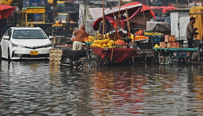 Fruit carts are pictured half submerged in a flooded street after rainfall in Karachi on February 4, 2024. — AFP