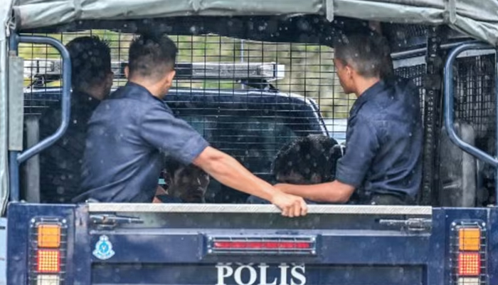 Malaysian police escort detainees towards the immigration detention center in Bidor in Malaysias northern Perak state on Feb 2, 2024. — AFP