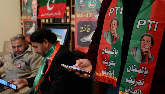 Pakistans former PM Imran Khans supporters wear scarves with prints of his PTI party on February 3, 2024. — AFP