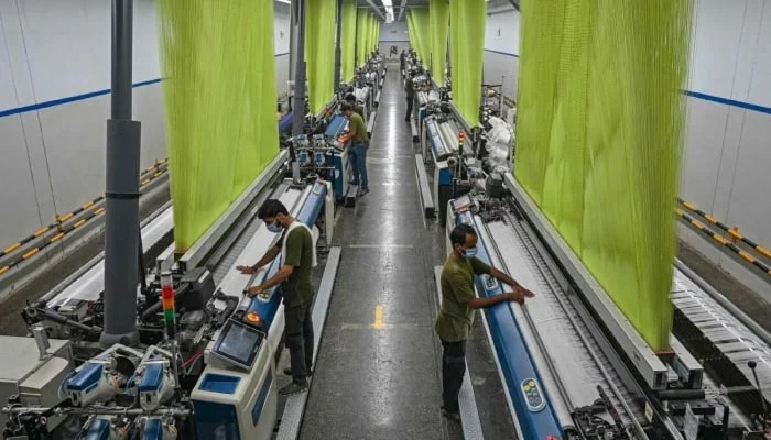 A worker operates a machine preparing fabric at the Textile Mills in Lahore on July 20, 2023. — AFP