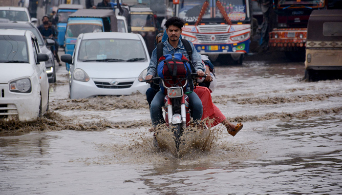 Vehicles passing through rainwater accumulated on the Korangi road during heavy rain that was experienced in Karachi. — APP