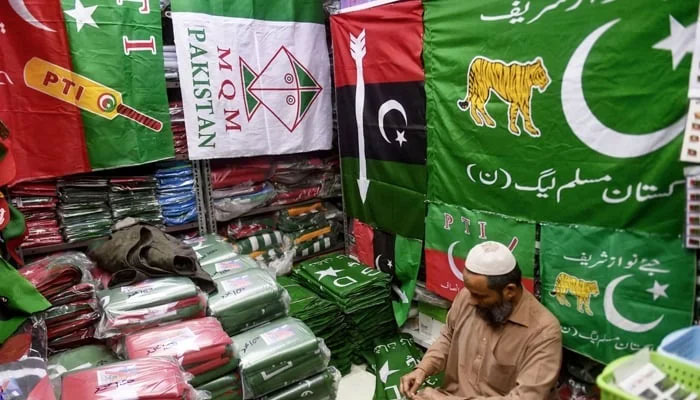 A shopkeeper arranges flags of political parties at his shop ahead of the upcoming general elections in Karachi. — AFP/File