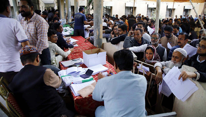 Polling staff gather ballot boxes and election materials for their polling station from the Election Commission Distribution Center in Karachi on February 7, 2024. — AFP