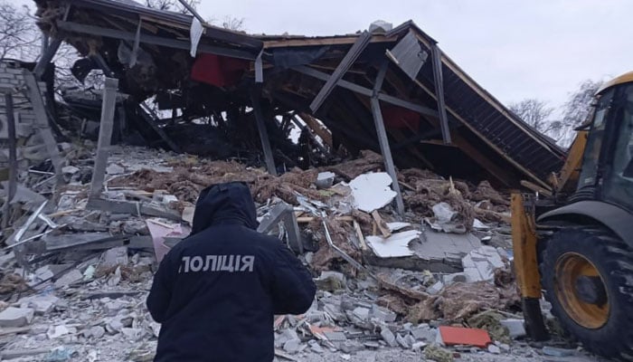 This image shows a policeman standing next to a building destroyed as a result of a missile attack in Zolochiv, Kharkiv region in northeastern Ukraine on February 6, 2024. — AFP