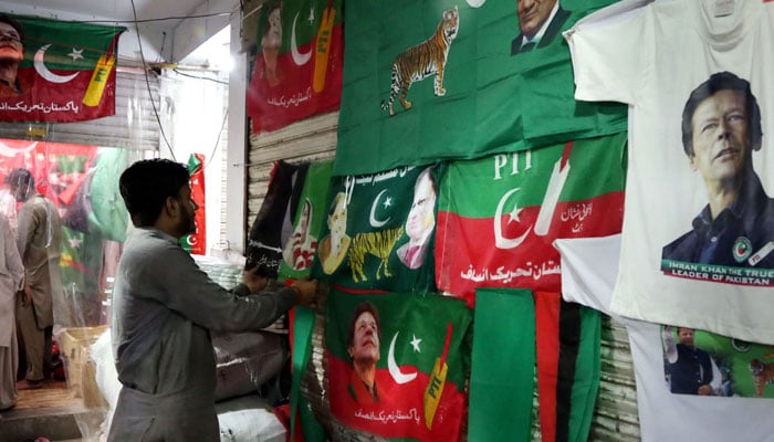 A salesman is hanging different political parties shirts to attract his customers for the upcoming general elections at Bhatti Gate in Lahore. — Online/File