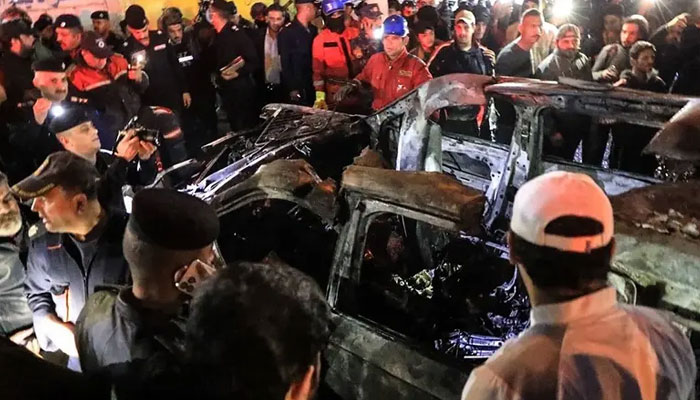 People, rescuers, and security forces gather around a vehicle hit by a drone strike, reportedly killing three people, in Baghdad on February 7, 2024. — AFP