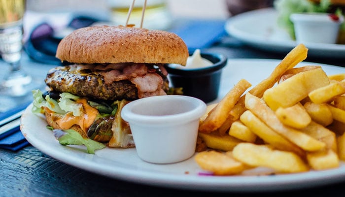 This representational image shows a burger and chips. — Unsplash/File