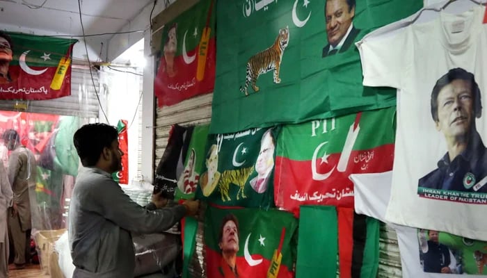 A salesman is hanging different political party shirts to attract his customers for the upcoming general elections at Bhatti Gate in Lahore. — Online/File
