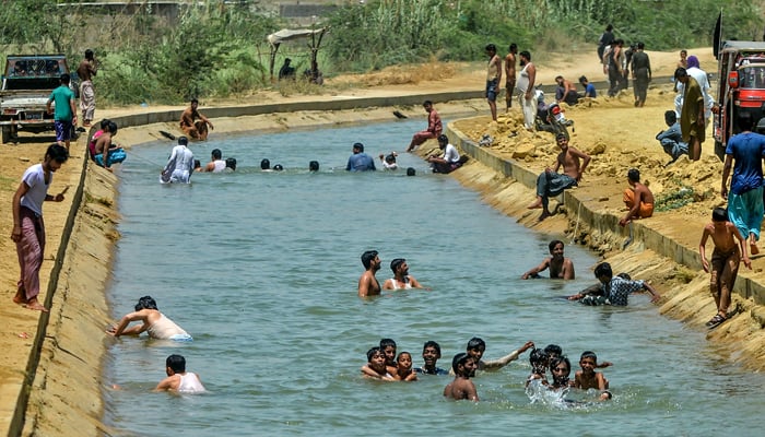 Youths jump a water canal in Karachi. — AFP/File