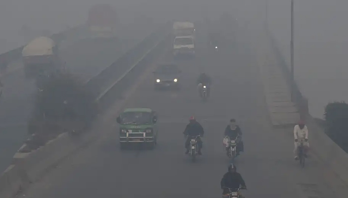 Commuters drive their vehicles through heavy smog in Lahore. — AFP/File