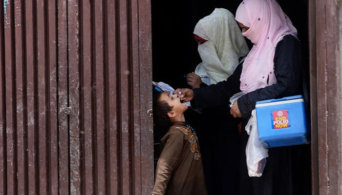 A health worker administers polio vaccine drops to an Afghan refugee child during a polio vaccination campaign in Lahore. — AFP/File