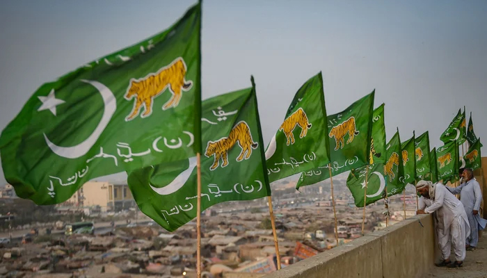 Workers install flags of the Pakistan Muslim League Party on the rooftop of a building, ahead of the upcoming general elections, on January 24, 2024. — AFP