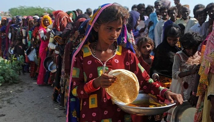 Internally displaced people gather to receive free food near their makeshift camp in the flood-hit Chachro of Sindh province. — AFP/File