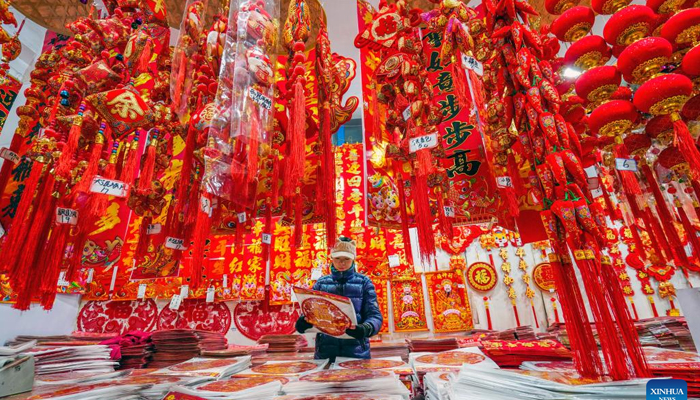 A customer selects decorations for the Spring Festival at a market in Yutian County, north Chinas Hebei Province, January 13, 2024. — Xinhua