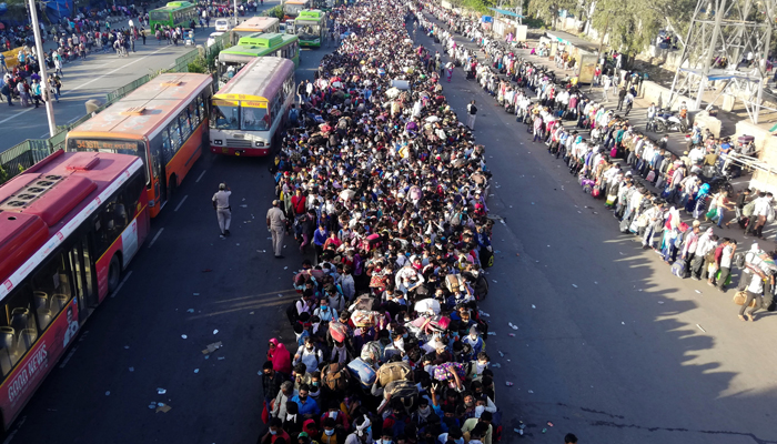 Migrant workers and their family members lineup outside the Anand Vihar bus terminal to leave for their villages. — AFP/File