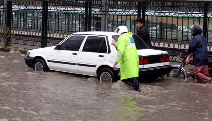 A traffic policeman is busy to facilitate people during the downpour of the winter season, at University Road in Peshawar on February 19, 2024. — PPI