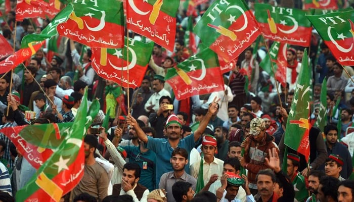 PTI supporters and workers hold flags in a rally. — AFP/File