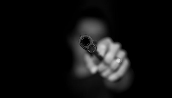 A representational image of a person holding a gun. — Unsplash
