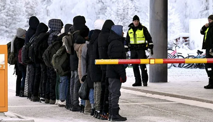 Migrants stand in a line in front of Finnish Border Guards at the international border crossing at Salla, northern Finland. — AFP/File