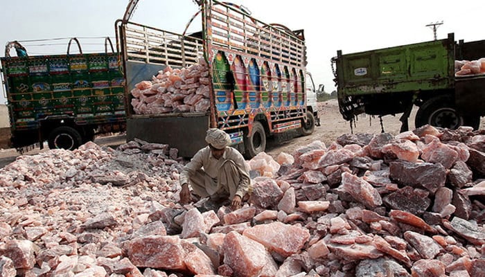 A Pakistani worker collects salt stones to be loaded onto a truck outside the Khewra salt mine. — AFP/File