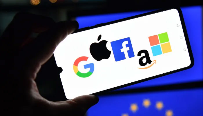 The logos of Google, Apple, Facebook, Amazon, and Microsoft are displayed on a mobile phone with an EU flag pictured in the background. — AFP/File