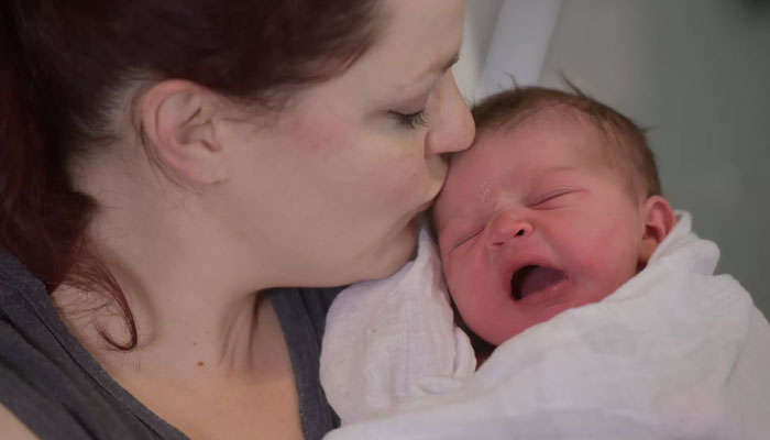 A representational image shows a woman kissing an infant. — AFP