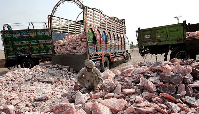 A Pakistani worker collects salt stones to be loaded onto a truck outside the Khewra salt mine in Khewra. — AFP/File