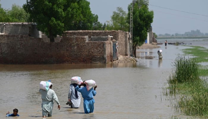 Flood affectees can be seen walking into floodwater in Sindh after devastating floods in 2022. — AFP/File