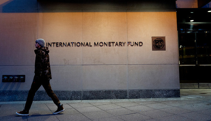 A pedestrian walks past the International Monetary Fund (IMF) headquarters in Washington, DC. — AFP/File