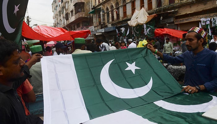 People buy national flags of Pakistan at a market ahead of Pakistans 75th Independence Day in Karachi. — AFP