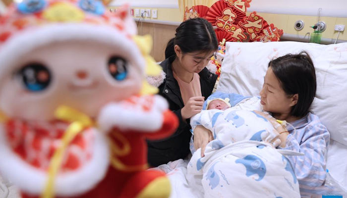 A newborn baby, whose Chinese zodiac sign is dragon, is seen with the mother and sister at a hospital in Wuxi, east Chinas Jiangsu Province, February 10, 2024. — Xinhua/Zhu Jipeng