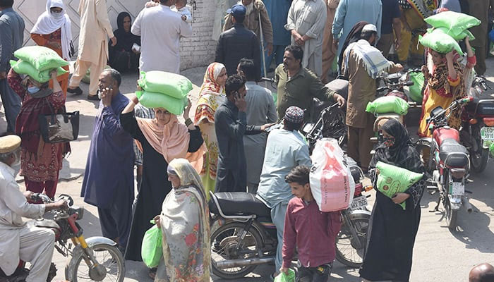 People stand in a queue to collect free wheat flour bags from Ramadan Package in Lahore, on March 28, 2023. — Online