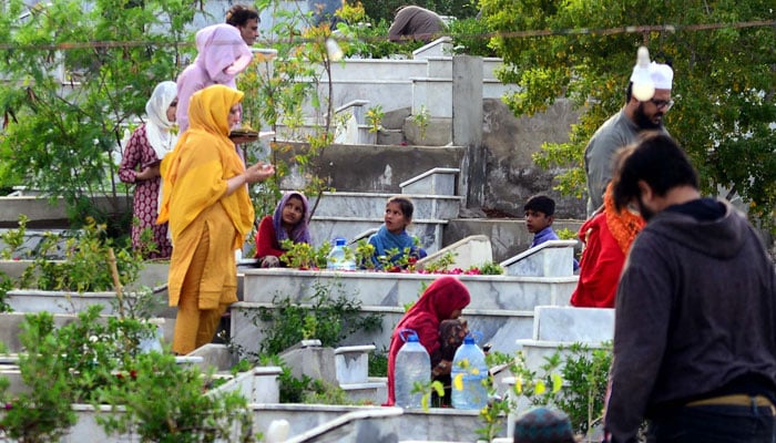 Family members are laying rose petals and offers Fateha on their visits graves of their loved ones, on the occasion of Shab-e-Barat at Tariq road Graveyard in Karachi on February 25, 2024. — PPI