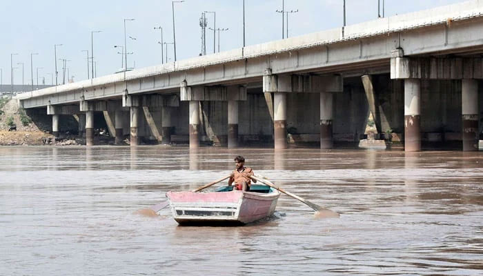 A man rows his boat in River Ravi after India unexpectedly diverted excess water into the river. — Online/File