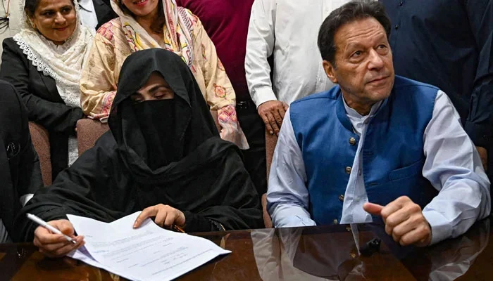 Former PM Imran Khan (right) along with his wife Bushra Bibi (centre) signs surety bonds for bail in various cases, at the registrars office in the Lahore High Court on July 17, 2023. — AFP